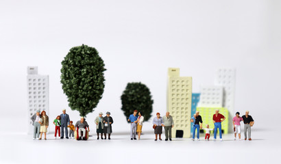 Any of various miniature families standing in front of miniature trees and miniature building.