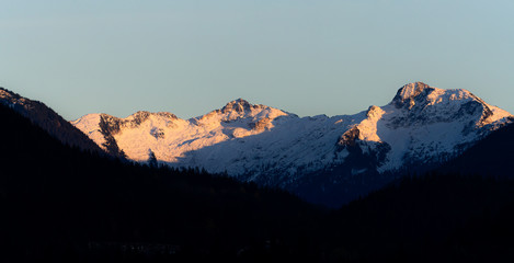 Pink and orange last light on snow covered mountains during sunset in winter in Canada