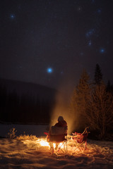 People camping under starry sky near campfire in winter in remote landscape in  Canada - 307535159