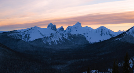 Obraz premium Pink and orange last light on snow covered mountains during sunset in winter in Canada