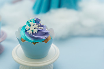 Set of tasty cupcakes with blue and purple cream icing on a pink tray on blue background and defocused lights. Selective focus. Pastel colors. Party concept. Children's party decoration.