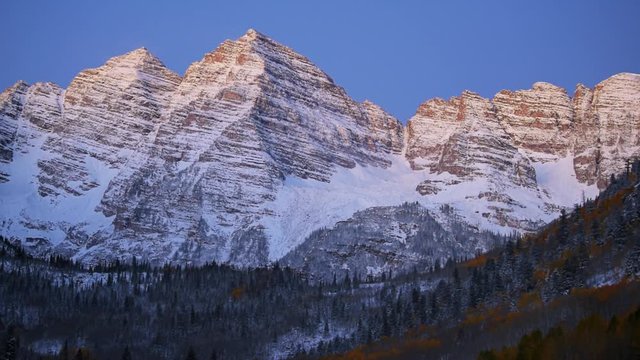 Maroon Bells morning sunrise timelapse with sunlight on peak in Aspen, Colorado rocky mountain and autumn yellow foliage panoramic view closeup and winter snow