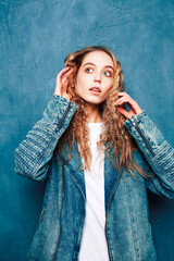 young pretty hipster girl with curly hair posing emotonal on blue wall background, lifestyle people concept