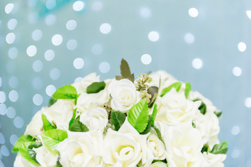 Close up of beautiful bouquet of white roses on blue background and blurred lights. Focus selective.
