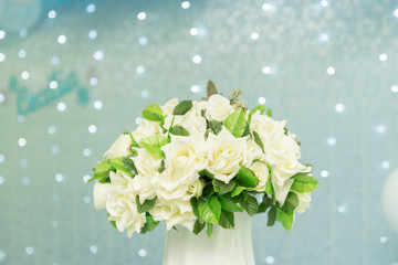Close up of beautiful bouquet of white roses on blue background and blurred lights. Focus selective.