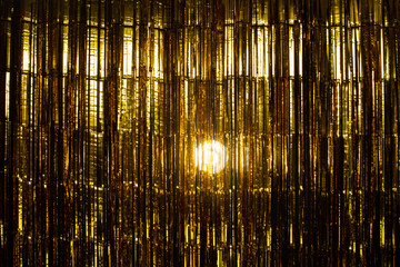 Gold Foil strip Curtain hanging on wall with studio lighting, Golden decorate Wallpaper Background Texture Detail with yellow reflect shinning for celebrating New Year or anniversary party concept