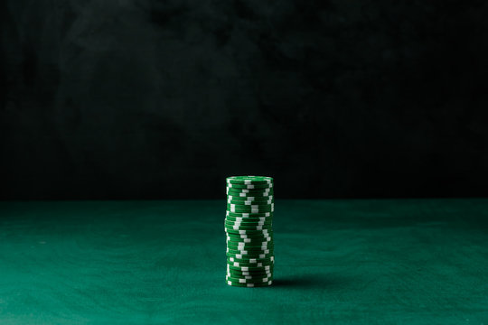 Stack of poker green chips on the table on a black background