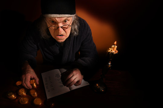 Old Scrooge busy counting his gold coins beside a candle