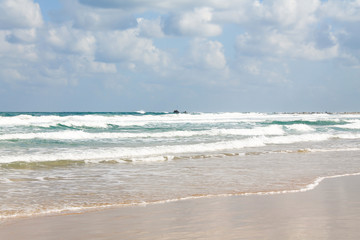Fototapeta na wymiar Sea foam on the sandy beach at Bat Yam, Israel. Waves on the blue stormy sea. Mediterranean coastline. Travelling picture. Turquoise water and sandy beach