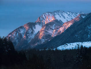 Pink and orange last light on snow covered mountains during sunset in winter in Canada - 307540159