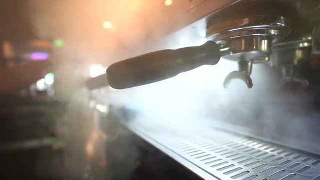 An espresso machine letting off some steam in slow motion in a coffee shop.