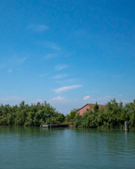 Fototapeta na wymiar House behind trees by water near island of Torcello, Venice, Italy