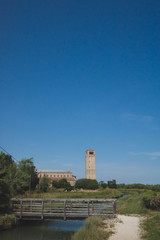 Cathedral of Santa Maria Assunta and bell tower by river on island of Torcello, Venice, Italy