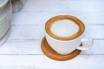 A cup of hot latte on a white wooden table