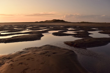 A small puddles in the sand after low tide in sunset light