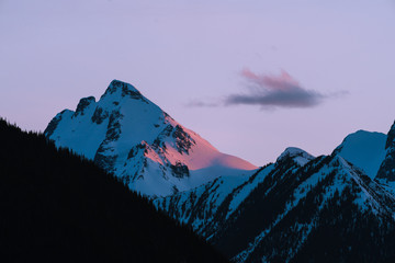 Pink and orange last light on snow covered mountains during sunset in winter in Canada - 307542351