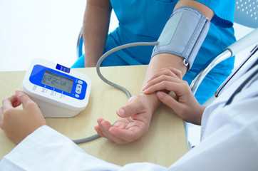 A female doctor checking blood pressure of a patient in the hospital