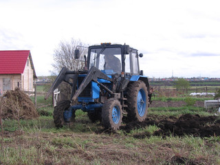 the tractor plows the land in the field rural labor in the spring digs up the garden
