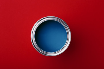 Can of classic blue paint on dark red background. Top view, color of year.