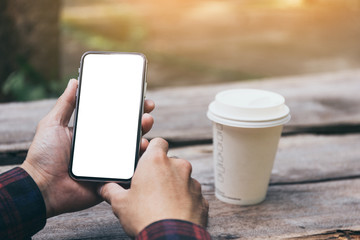 Mockup image blank white screen cell phone.men hand holding texting using mobile on desk at home office. background empty space for advertise text.people contact marketing business and technology 