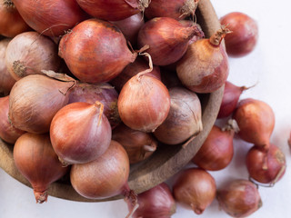 Raw red onion in old wooden bowl on white background. selective focus
