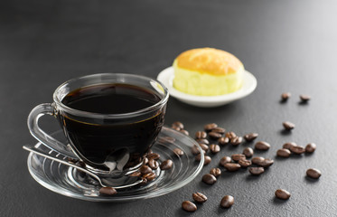 Black coffee in a coffee cup and with saucers Complete with coffee beans and bread on the black table