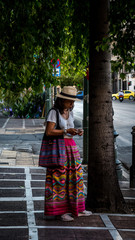 Asian woman in white t-shirt in Athens in sarong standing on street