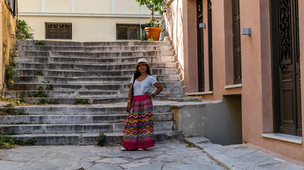 Asian woman in white t-shirt  in Athens in white hat and sarong standing in front of marble stairway