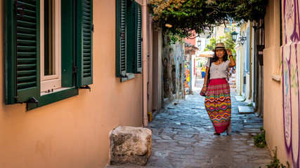 Asian woman in white t-shirt  in Athens in white hat and sarong standing in the middle of small road