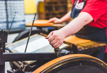 A university student uses an old printing press in a college printmaking class.