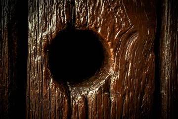 Hole on dark brown wooden background.