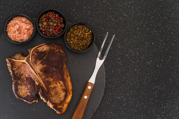 T-bone porterhouse beef steak meat with chimichurri sauce against black stone background