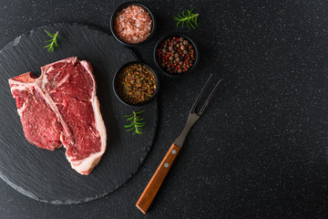 Raw t-bone porterhouse beef steak meat with chimichurri sauce against black stone background