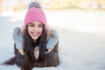 attractive cute girl lying on snow in hat and mittens in winter in Park copy space