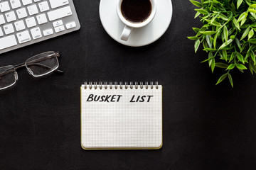 Bucket list. Blank notebook to write goals and wishes on black office desk top-down