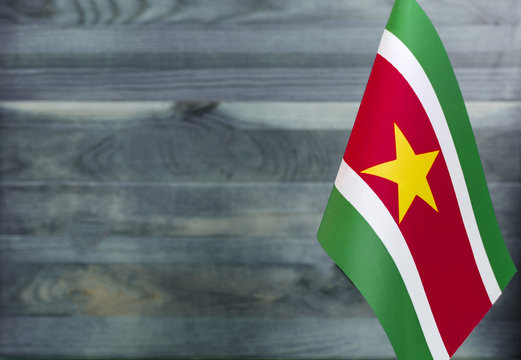 Fragment of the flag of the Republic of Suriname in the foreground blurred light background copy space