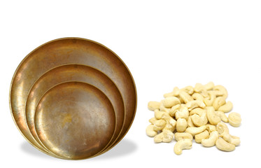 Antique copper plate with cashew nuts heap on white background.