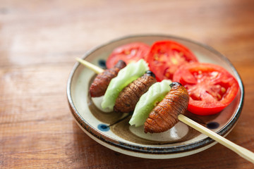 Fried Worm, Insect food in the skewer with wooden table background. Closeup, Selective focus.