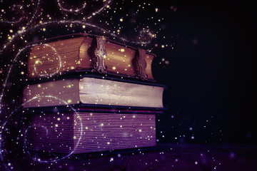 stack of antique books on old wooden table. fantasy medieval period and religious concept. Glitter sparkle lights © tomertu