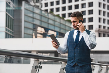 Businessman speaks by mobile phone and look at tablet computer