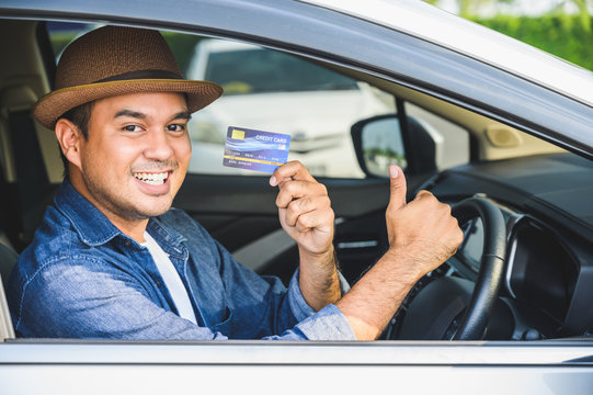 An Asian man is holding a credit card in his hand. While he was driving This picture is about shopping. Spending money Expenses related to car bills by credit card