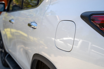 Obraz premium Close up shot of a car fuel tank lid. with warm light. white car.