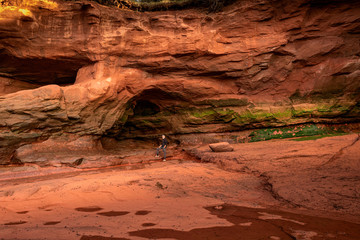 A tourist dwarfed by rock formations carved out by the sea at Burntcoat Head in Nova Scotia, Canada