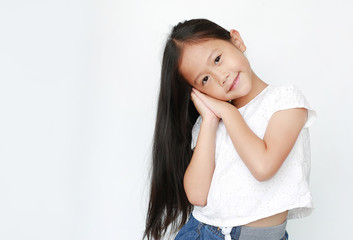 Beautiful caucasian little child girl sleep gesture posing with hands together while smiling with looking at camera isolated over white background.