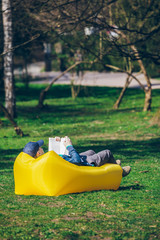 book reading concept. man in city park on inflatable mattress