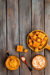 Trendy dessert - salted caramel - melted and cubes on dark wooden background top view frame copy space