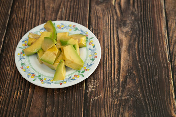 Chopped avocado on a plate on a wooden background