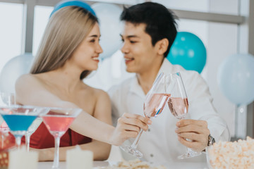 Young couple celebrating new year together, selective focus at cocktail glasses.