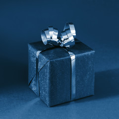 Classic gift box on blue background. Minimal styled holiday concept. Shot at angle.