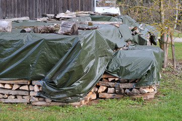 firewood covered with a tarpaulin on a farmyard